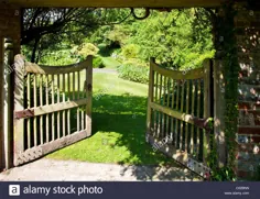 عکس - یک دروازه باغ چوبی باز در یک باغ روستایی انگلیسی که نمایی از باغ وسیع تر از آن را نشان می دهد