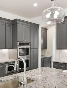 میزهای آشپزخانه گرانیتی با کابینت هایی به سبک شیکر خاکستری و صفحه پشتی کاشی سفید.  ضد زنگ