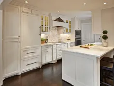 آشپزخانه ای خیره کننده با کابینت سفید و کف تخته های چوب سخت