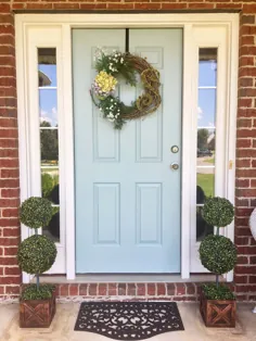 درب ورودی آبی روشن با تاج گل.  خانه آجر قرمز.  گیاهان ایوان.