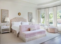 یک اتاق خواب زیبا با رنگ سفید و سفید با سرتختی منگوله دار ، ستون صورتی کم رنگ ، پنجره هایی پر از نور