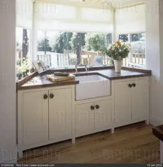 تصویر سهام - پنجره خلیج آشپزخانه با میز کار چوبی و سینک ظرفشویی بلفاست که در قسمت کمد سفید تعبیه شده است.  توسط www.DIOMEDIA.com