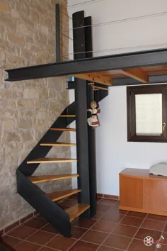 Escalera de caracol con peldaños de madera y altillo de diseño con acero pintado de forja y barandilla de sirga افقی