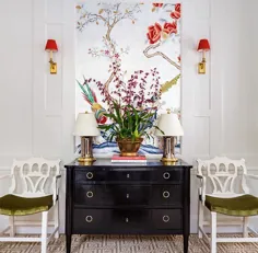 یک فضای متقارن با کمد مشکی ، نقاشی دیواری ظریف گل روی یک دیوار سفید ، و دو صندلی سفید