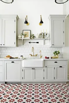 سینک ظرفشویی بزرگ سفید در آشپزخانه تمام مزرعه سفید با کاشی های کف طرح دار.