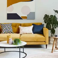 اتاق نشیمن مدرن با مبل زرد خردلی ، آثار هنری انتزاعی و میز قهوه خوری مرمر گرد |  خانه ایده آل