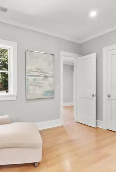 اتاق نشیمن معاصر.  دیوارهای خاکستری روشن  کف های چوبی سبک  صندلی های کرم مخمل خواب دار.  تر و تمیز سفید