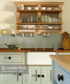 عکاسی SuperStock Stock، قفسه بشقاب چوبی در بالای غرق سفید بلفاست در آشپزخانه با واحدهای مجهز به رنگ سبز کم رنگ