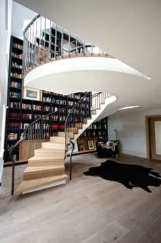راه پله مارپیچ بدون زحمت توسط قفسه کتاب از کف تا سقف جریان می یابد