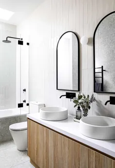 آینه های قوسی با قاب سیاه و سفید و حوضه های بتونی گرد ، لطافت را به این فضای حمام اضافه می کنند
