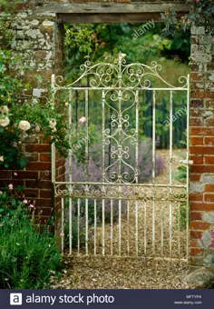 عکس - دروازه باغ فلزی سفید رنگ در دیوار آجری