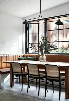 این ناهار خوری مدرن دارای یک صندلی ضیافت چرمی برنزه است که با پنجره های قاب فولادی ست شده است