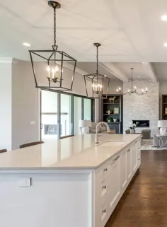میز آشپزخانه کوارتز با کابینت هایی به سبک شیکر سفید ، نقشه کف باز ، آویز ، کف چوبی.